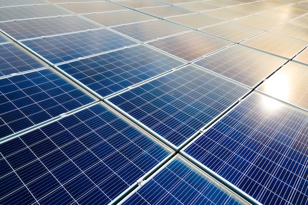 Aerial view of surface of blue photovoltaic solar panels mounted on building roof for producing clean ecological electricity. Production of renewable energy concept.