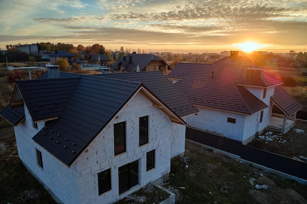 Aerial view of unfinished house with aerated lightweight concrete walls and wooden roof frame covered with metallic tiles under construction