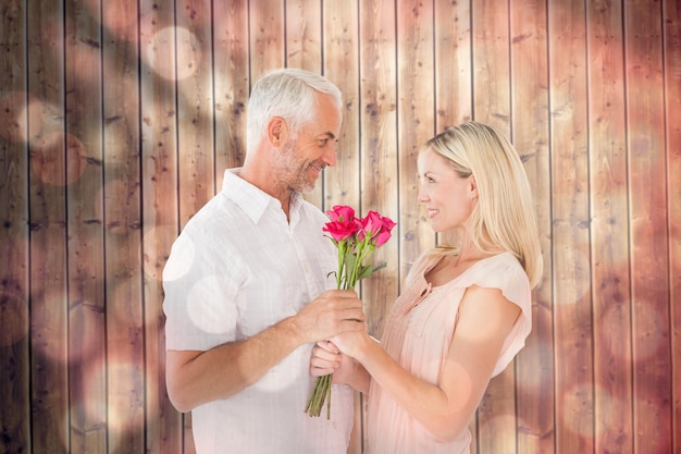 Affectionate man offering his partner roses against light circles on black background