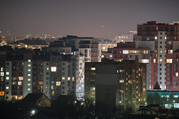 Architectural details of modern high apartment buildings with many illuminated windows and balconies at night