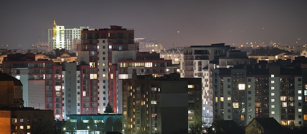 Architectural details of modern high apartment buildings with many illuminated windows and balconies at night