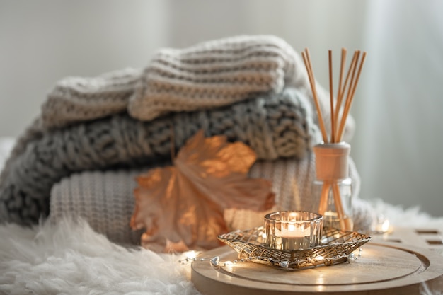 Aroma bamboo sticks in a bottle with scented liquid with candles staying on a wooden tray on blurred background.