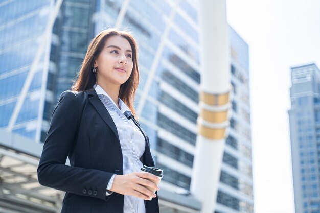 Photo asian beautiful businesswoman holding coffee cup standing in the city