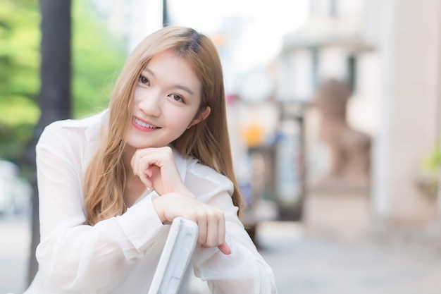 Photo asian beautiful girl with bronze hair in white shirt while sits happy smilie on the edge