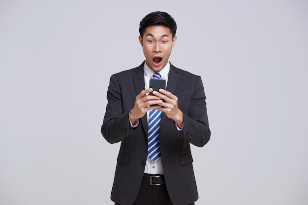 Asian businessman using smartphone and surprise to receive notification