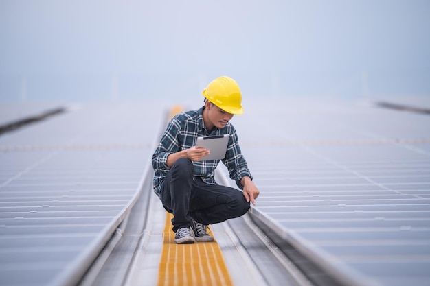 Photo asian engineer using tablet checking in solar power system for industrial ecology control top roof factory