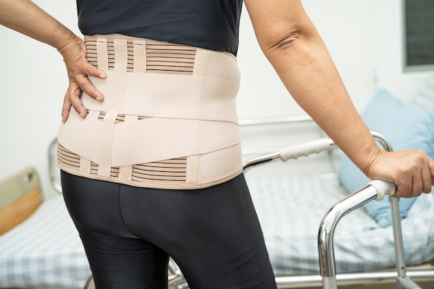 Asian lady patient wearing back pain support belt for orthopedic lumbar with walker.