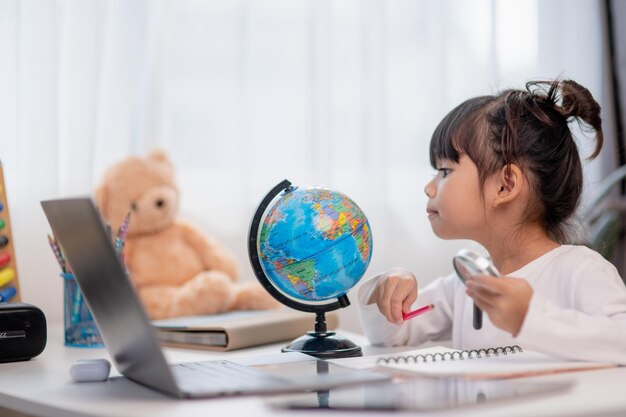 Photo asian little girl is learning the globe model concept of save the world and learn through play activity for kid education at home