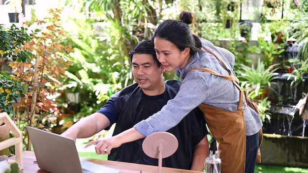 Asian love couple making haircut for refreshing his looks at home. Salon and barbershop in garden.