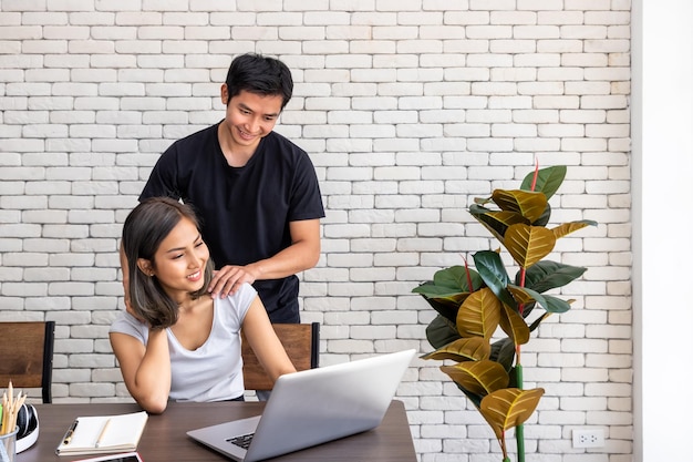 Asian man husband motivate support wife woman freelancer working at home sitting at desk dining table in living room