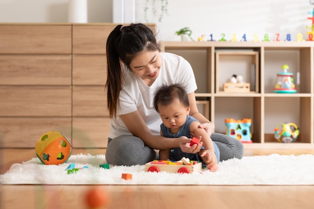 Photo asian mom teaching baby boy learning and playing toys for development skill at home or nursery room happiness mother and baby spending time together at warmth place good moment with mom and baby