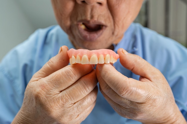 Photo asian senior woman patient holding to use denture in nursing hospital