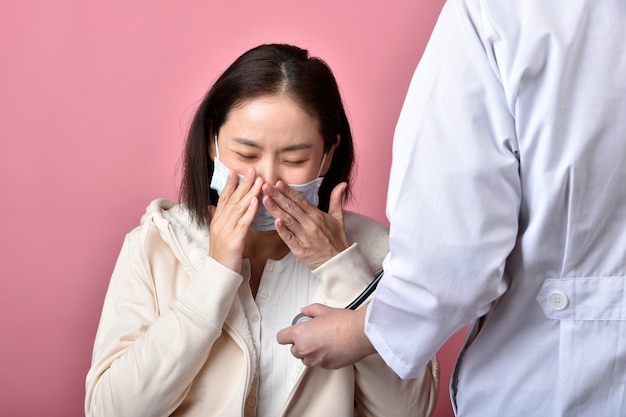 Foto la donna asiatica ha allergia alla gola e tosse nella maschera facciale, starnuti e tosse hanno diffuso la gocciolina della malattia di coronavirus, il dottore ha esaminato il paziente infetto covid-19 in ospedale.