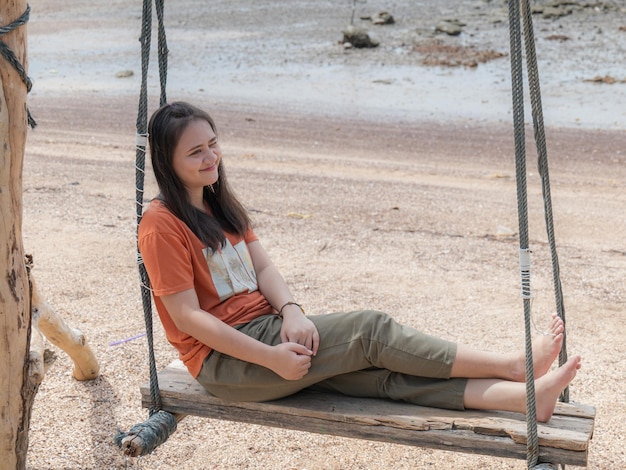 Photo an asian woman swings on a swing at the beach on a holiday in southern thailand.