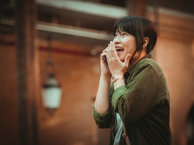 Photo アジアの女性がショッピングモールで幸せな気分でスマートフォンを使用して