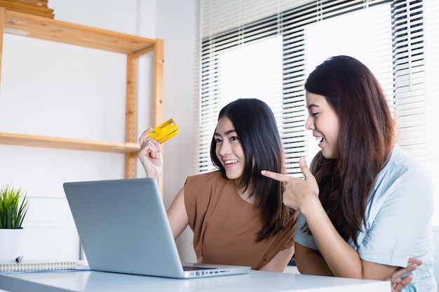 Asian women and her friend Using credit cards for fun online shopping