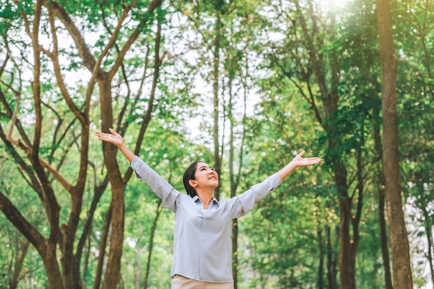 Photo asian women raise their hands to nature in the forest people protect from deforestation and pollution or climate change concept to love nature and tree environment ecology and earth day concept