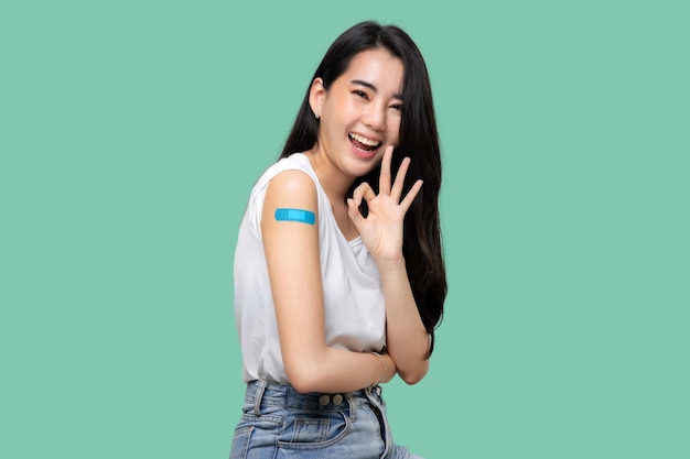 Asian Women Show Bandage On Arm Happy Asian Woman Feels Good After Received Vaccine Isolated On Green Background