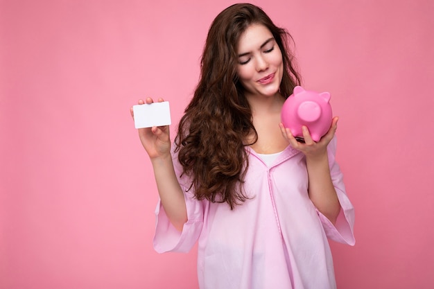 Attractive happy young brunette woman wearing shirt isolated on pink background with empty space and