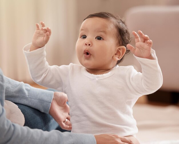 Photo baby excited and hands of mom in home for development motor skills and bonding in living room mother infant and dress for day with care energy and trust in parent for wellness and security