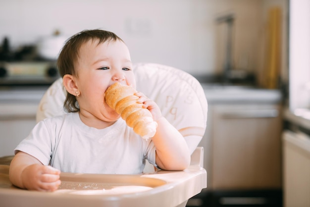 Baby in the kitchen eagerly eating the delicious cream horns, filled with a vanilla cream