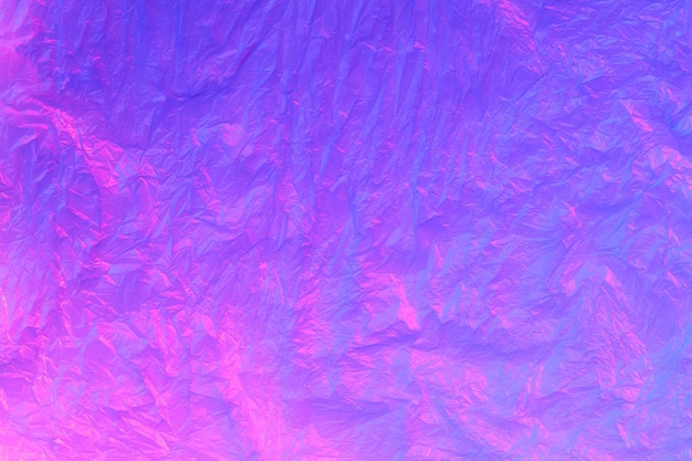 Background from purple recyclable polyethylene in neon pink light.