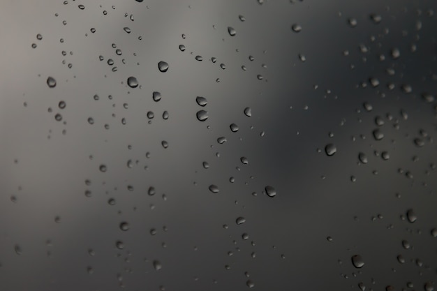 Background water drops. Raindrops on window panes. Natural pattern of rain drops. Abstract shot of raindrops on glass. Abstract falling rain drop of rain on glass. Place for an inscription or logo