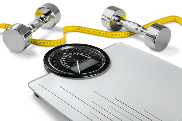 Photo bathroom scale with a measuring tape and dumbbells on background