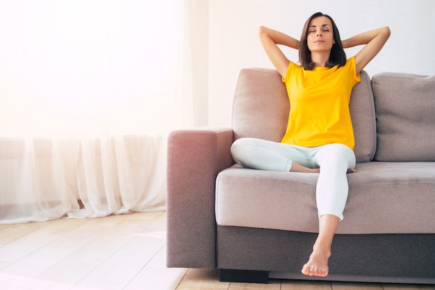 Beautiful calm confident brunette woman is resting on the couch at home during holidays