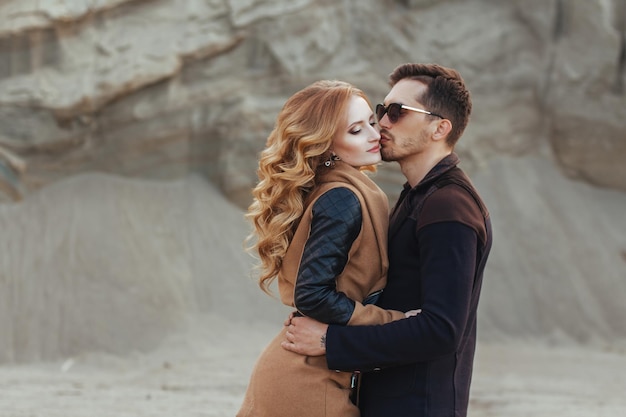 Beautiful couple in love on Valentine's Day. Happy young couple walking on the sandy mountains on a cloudy day