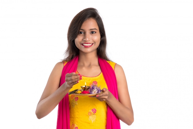 Beautiful Indian young girl holding pooja thali or performing worship on white