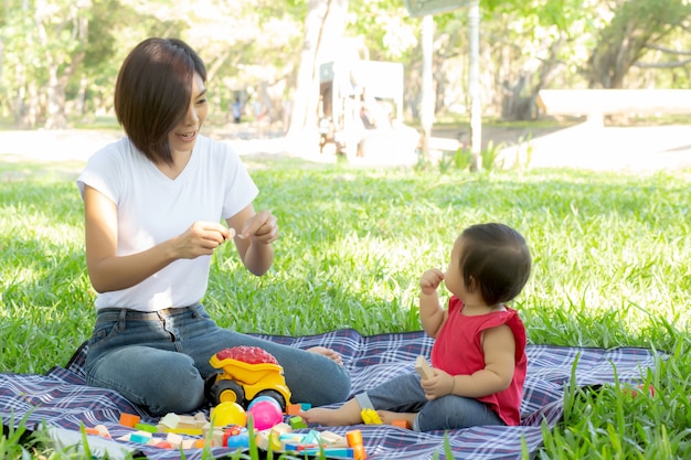 Beautiful young asian mom and daughter playing toy blocks for learning development happy