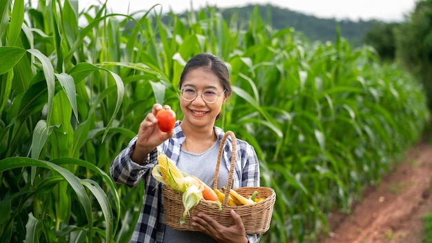 Photo beautiful young brunette portrait famer woman hand holding vegetables in the bamboo basket on green