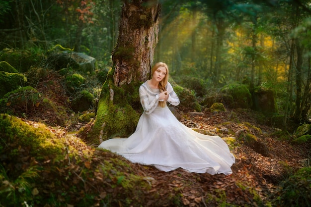 Beautiful young woman in a white dress in the middle of a forest