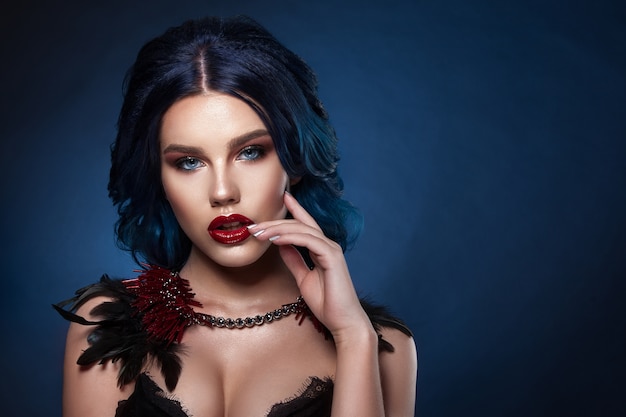 Beauty face of a girl with blue hair with a braid hair. Professional make-up, clean skin, shot against a dark background.