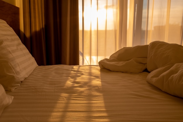 Bed with white linens at sunriseSleeping place with pillows and a blanket at dawnResvet in the bed