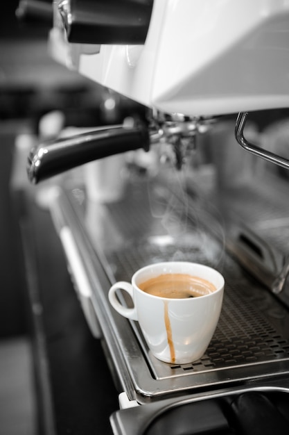 Black coffee in white cup put on coffee maker