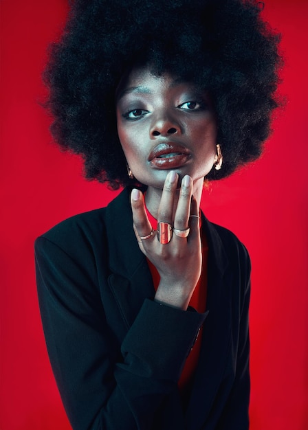 Black woman portrait and afro hair and beauty with makeup and shine isolated on red background Hairstyle haircare and texture with growth face skin glow and confident African model in a studio