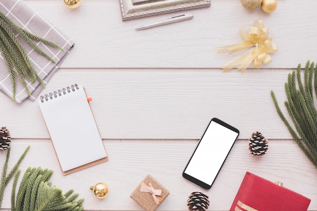 Blank screen smartphone with Christmas composition on white wood table