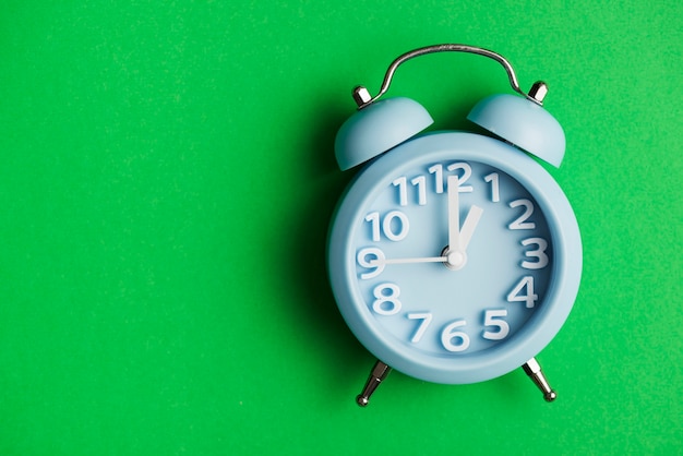 Blue alarm clock against green background