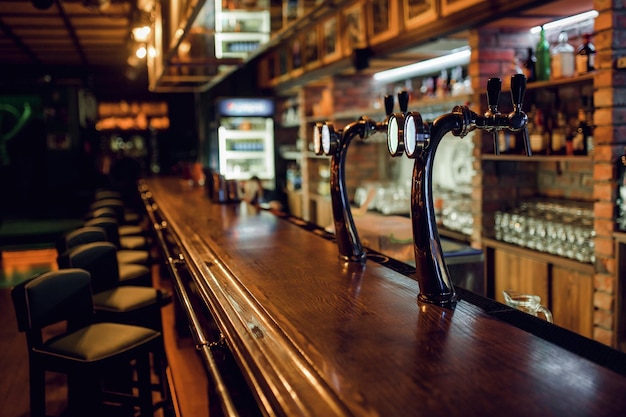 Photo blurred background of classic wooden bar counter with empty chairs and alcohol in the background