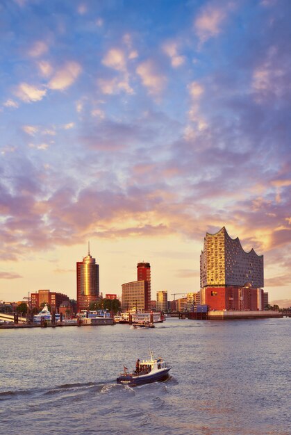 Photo boat with tourists goes towards elbphilharmonie in hamburg at sunset