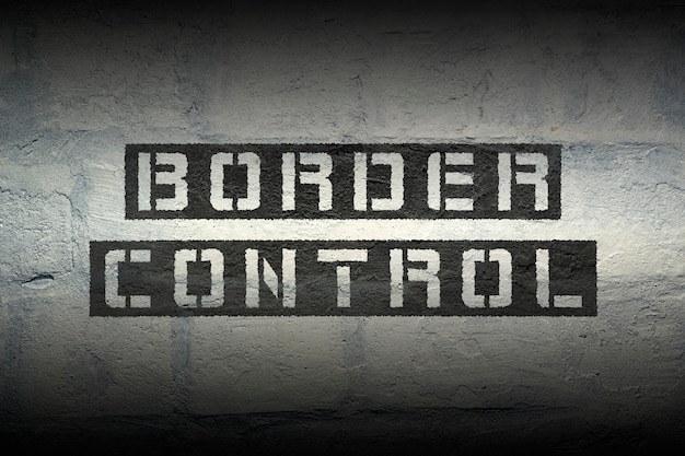 Border control stencil print on the grunge white brick wall