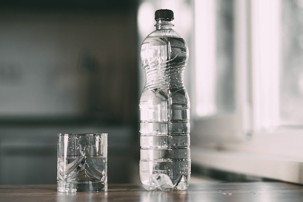 Bottled water and a glass on the table at home in the kitchen