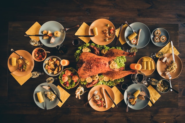 Boven boven hoge hoek foto van grote gebakken gebraden gevulde kalkoensalade decor midden van het diner godzijdank maaltijd volledige borden garnering geel servet twee kaarsen in woonkamer zonder mensen binnenshuis