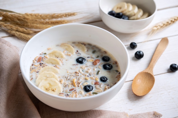 Photo bowl of granola almond and grains with blueberry and banana on wooden table, healthy breakfast