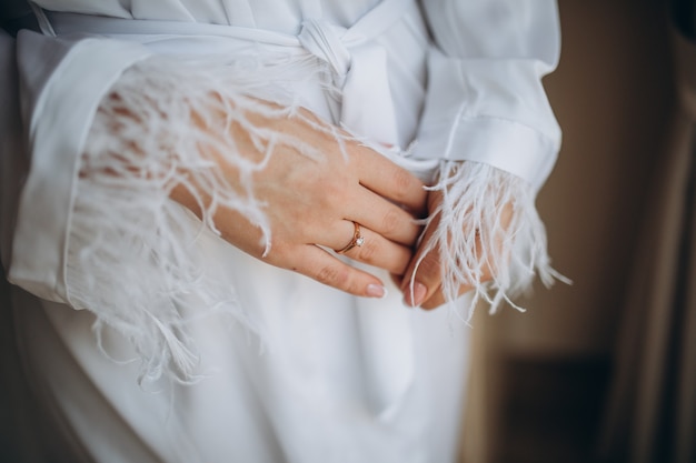 the bride holds a gold wedding ring with a diamond