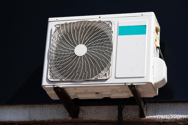 Buitenunit van een huishoudelijke airconditioner met een ventilator buiten het gebouw