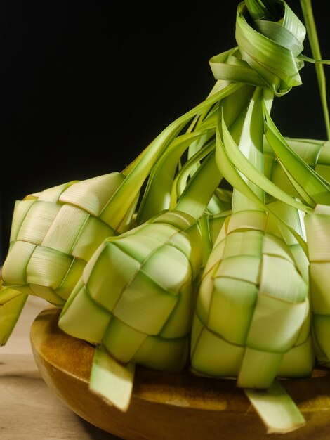 Foto un mazzo di ketupat verde su un piatto di legno