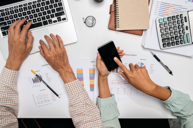 Business team using laptop computer and smartphone to work with financial data.